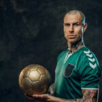 Handsome soccer player holding a golden soccer ball